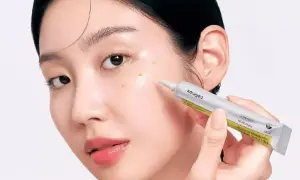 Une femme applique un sérum sur son visage. Le tube indique "RETINAL", suggérant une discussion sur la différence entre rétinol et rétinal.