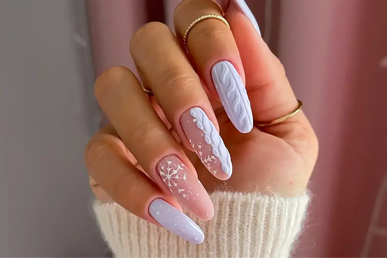 Manucure d'hiver avec des flocons de neige et un motif de pull tricoté sur des ongles longs. Un modèle ongle hiver parfait pour la saison.