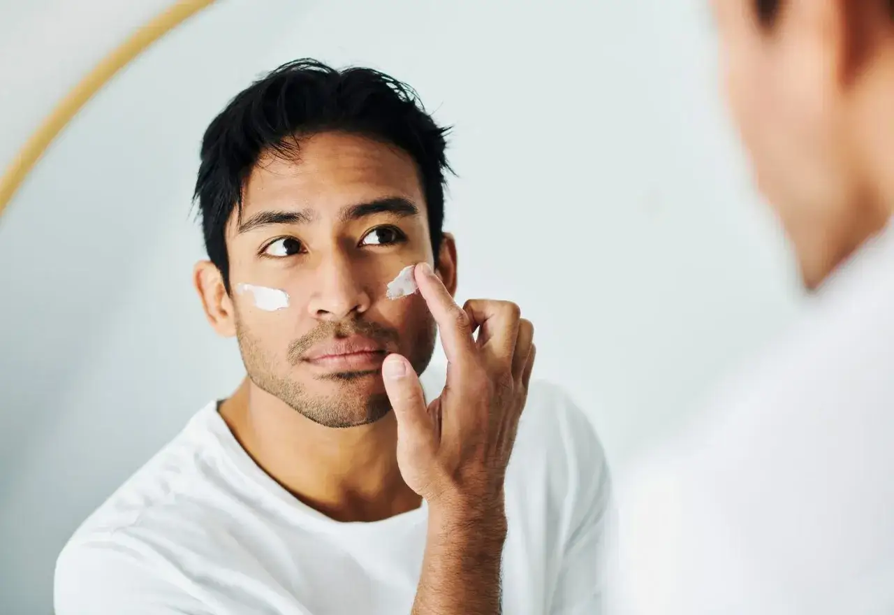 Un homme applique de la crème sur son visage. Est-ce que la crème solaire hydrate ? Cette crème semble hydratante.