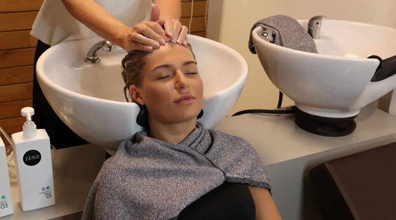 Une femme se fait laver les cheveux dans un bac de lavage. Apprenez comment faire un bon shampoing pour un moment de d&eacute;tente.