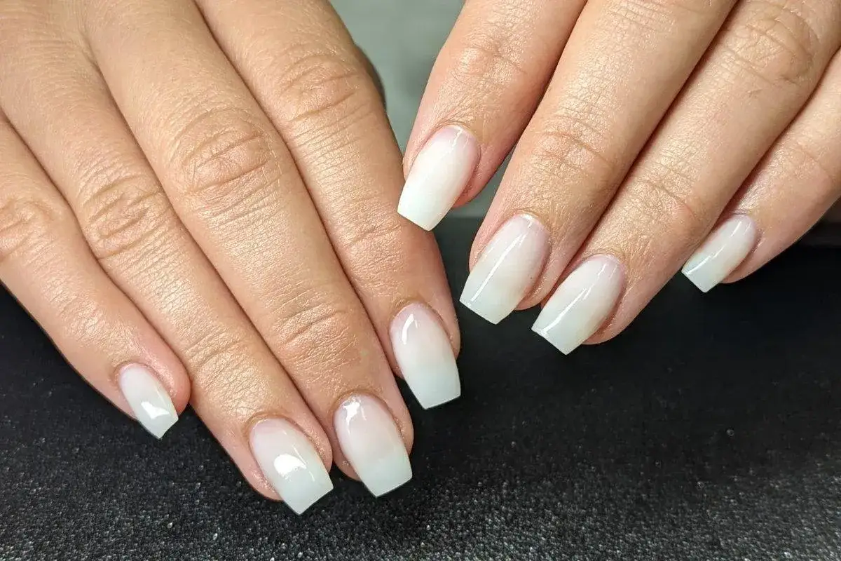 Mains d&eacute;licates aux ongles longs et carr&eacute;s, arborant une manucure blanche subtile et &eacute;l&eacute;gante, comme un voile de mari&eacute;e.